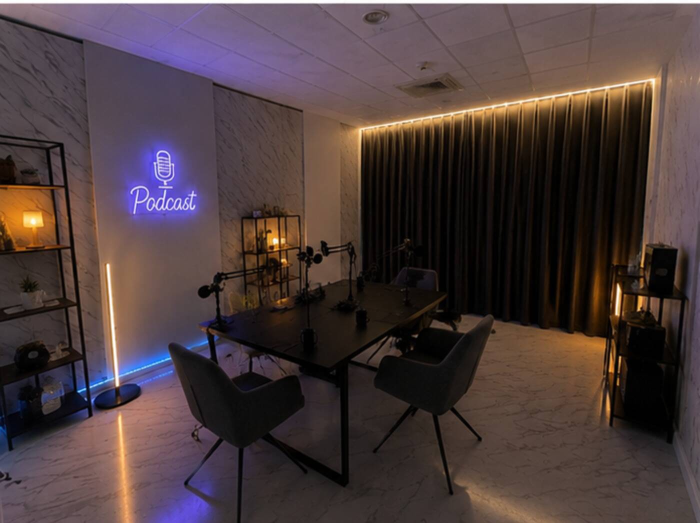 Sala 02 di Narciso Studios, studio podcast con tavolo per quattro, bracci microfono e insegna al neon Podcast